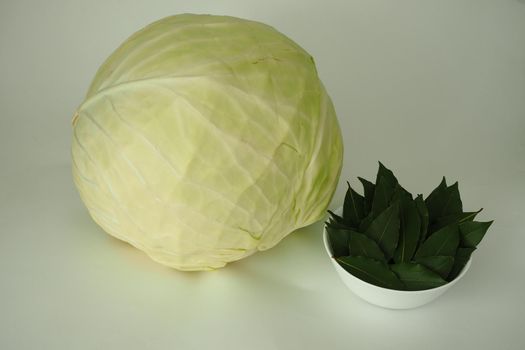 A large swing of white cabbage and a green bay leaf are isolated on a white background. High quality photo