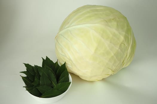 A large Velok of white cabbage and a green bay leaf are isolated on a white background. High quality photo