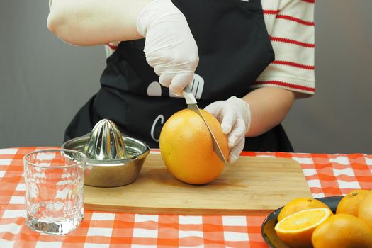 A young woman makes freshly squeezed juice from oranges and grapefruit on a hand-made juicer. High quality photo