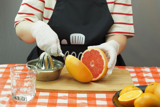 A young woman makes freshly squeezed juice from oranges and grapefruit on a hand-made juicer. High quality photo