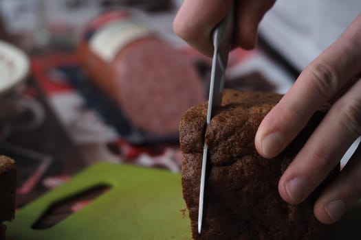 A young man makes a sandwich of black bread and sausage. High quality photo