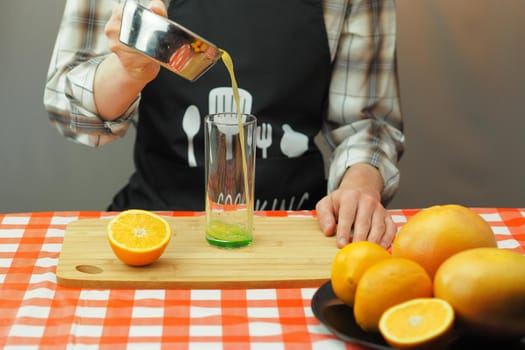 A young man pours freshly squeezed citrus juice into a transparent glass. High quality photo