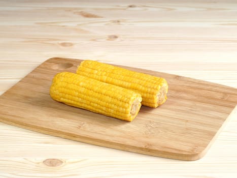 Boiled corn pob and sweet popcorn. Ears of cooked sweet corn on a wooden table scattered popcorn. Close-up, isolated. 