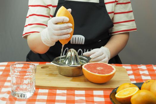 A young woman makes freshly squeezed juice from oranges and grapefruit on a hand-made juicer. High quality photo