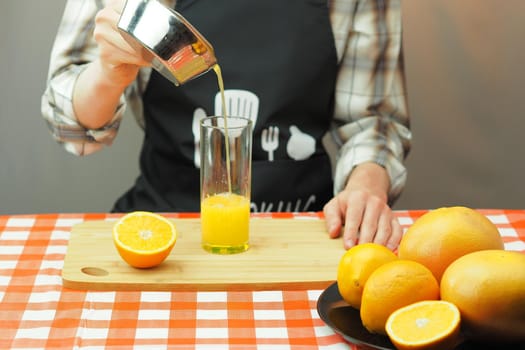 A young man pours freshly squeezed citrus juice into a transparent glass. High quality photo