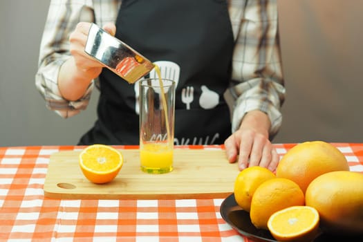 A young man pours freshly squeezed citrus juice into a transparent glass. High quality photo