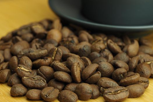 A beautiful background of natural coffee beans and a coffee cup in the background. High quality photo