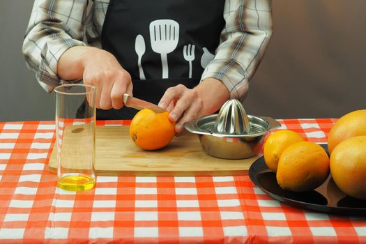 A young man in an apron makes freshly squeezed juice from orange and grapefruit. High quality photo