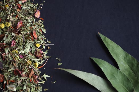 Dried herbs and flowers for herbal tea on a black background.