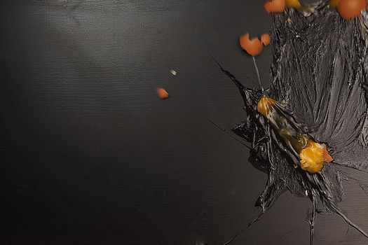 A broken egg on a black background. Raw egg texture yolk, protein and shell. Big, isolated. High quality photo