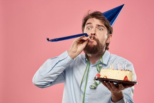Bearded man with cake tongue on a pink background cropped view and a blue cap on his head. High quality photo