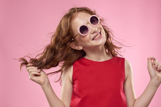 girl with curly hair sunglasses childhood joy pink background. High quality photo