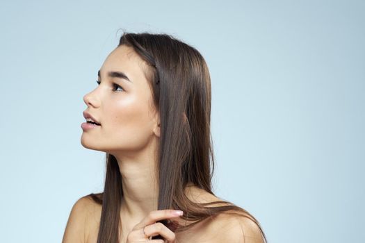 Pretty brunette with bared shoulders long hair body care blue background. High quality photo