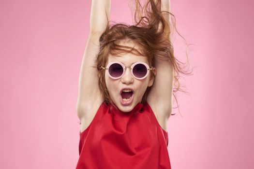 Cheerful little girl childhood dark glasses red dress lifestyle pink background. High quality photo