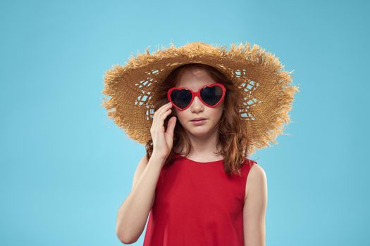 Girl in a beach Straw hat in sunglasses curly hair fun blue background. High quality photo