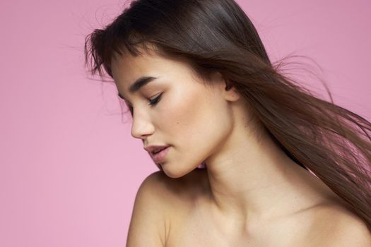 Pretty brunette naked shoulders clear skin pink background. High quality photo