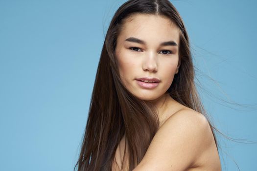 pretty brunette naked shoulders long hair skin care blue background. High quality photo
