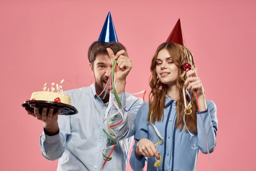 Party man and woman with cake on pink background corporate birthday. High quality photo
