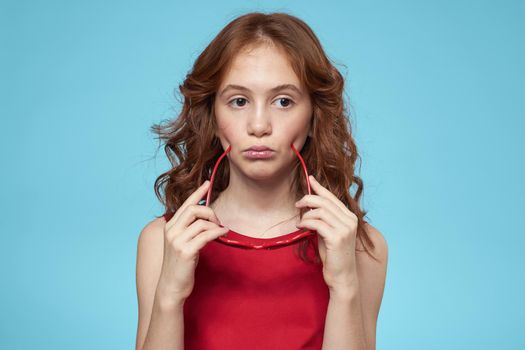 little girl with curly hair with a crown on her head red dress Smile blue background. High quality photo