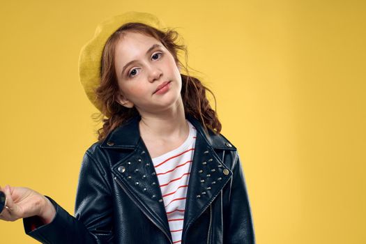 Cheerful little girl in sunglasses and hat lifestyle studio yellow background fashion. High quality photo