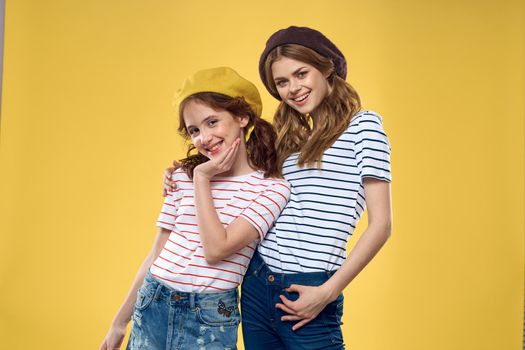 funny mom and daughter wearing hats fashion fun joy family yellow background. High quality photo