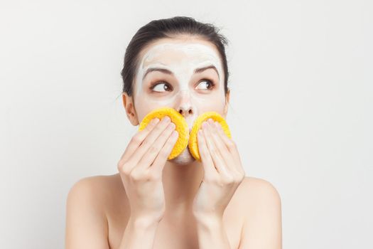Cheerful brunette wipes face mask with sponges cropped view. High quality photo