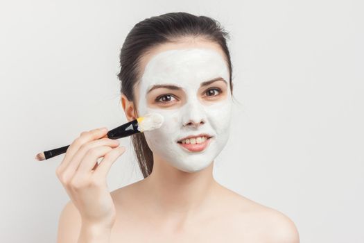 pretty woman with bare shoulders apply cream brush to face spa treatments. High quality photo