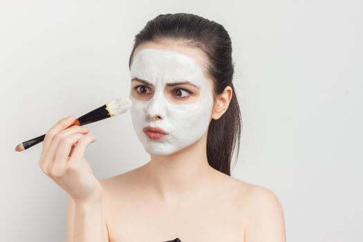 woman with bare shoulders as face mask brush for applying skin care. High quality photo