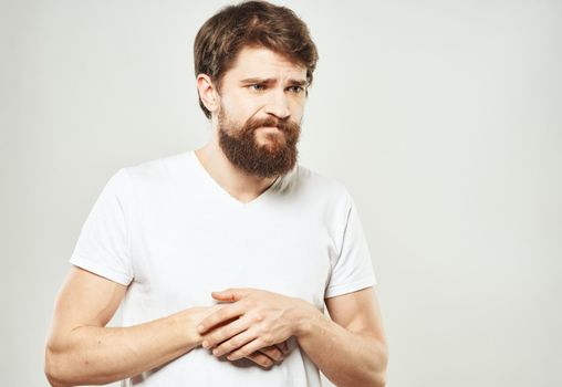 Guy in a white T-shirt on a light background emotions sad face cropped view. High quality photo
