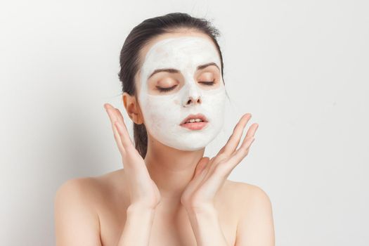 brunette with bare shoulders facial masking skincare. High quality photo