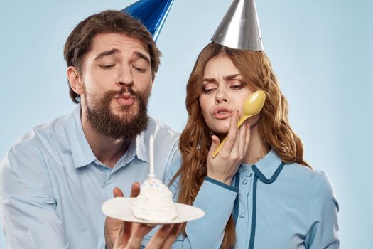 Cheerful man and woman with cake in a plate corporate party blue background. High quality photo