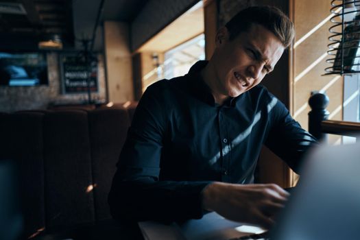 A business man in a cafe is sitting at a table while working in front of a laptop. High quality photo