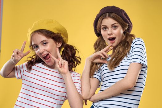 funny mom and daughter wearing hats fashion fun joy family yellow background. High quality photo