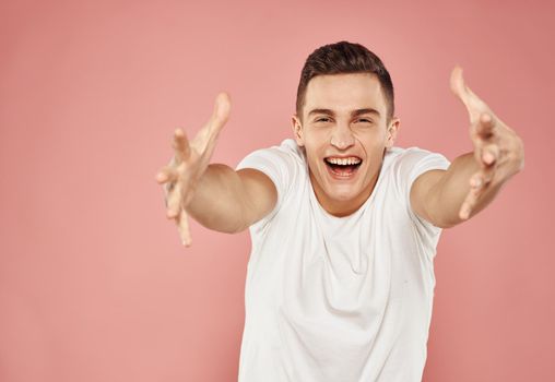 emotional man in white t-shirt gesturing with hands cropped view pink background. High quality photo