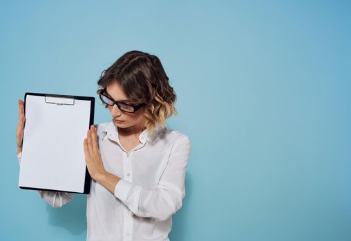 Business woman with a folder and a white sheet of paper on a blue background glasses on her face. High quality photo