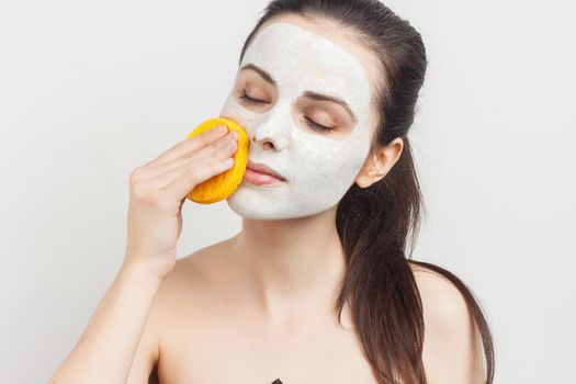 Cheerful brunette wipes her mask with a sponge scrub skincare. High quality photo