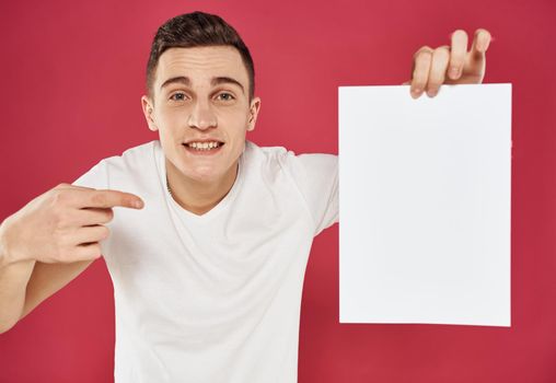 Man with a vertical sheet of paper on a red advertising background. High quality photo