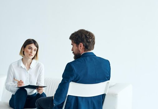 A woman psychologist with documents sits on the couch and a man . High quality photo