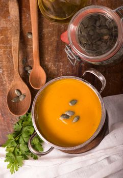 Bowl of pumpkin soup on rustic wooden background.