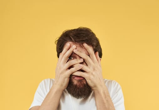 Upset man holds his hands near his face on a yellow background. High quality photo