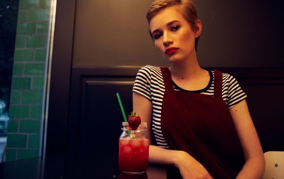 women in a sundress sitting in a cafe and looking at the street through the glass. High quality photo