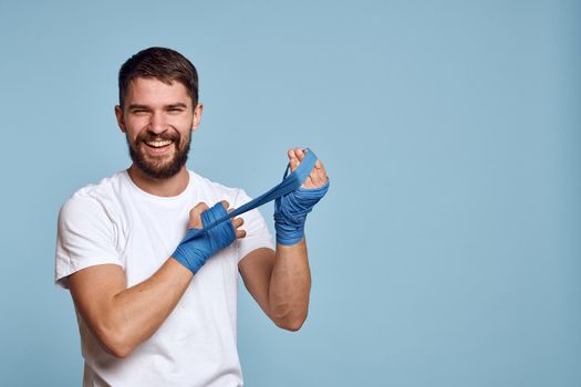 Man in white t-shirt sport boxing bandages energy blue background. High quality photo