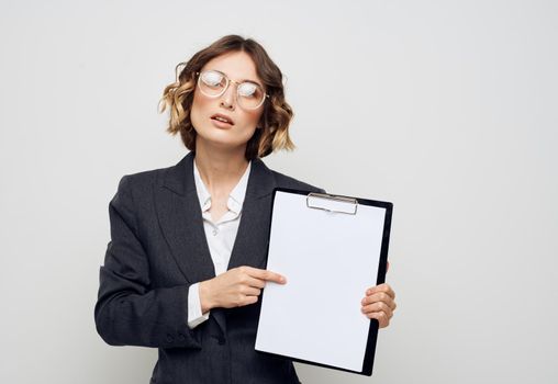 Business woman with documents gestures with her hands on a light background and glasses on her face. High quality photo