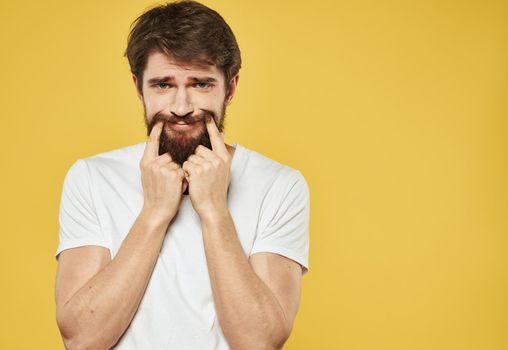 Emotional brunette man gestures with his hands on a yellow background. High quality photo