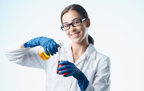 a nurse in a lab coat and blue gloves with a flask in her hand chemical element laboratory analyzes. High quality photo