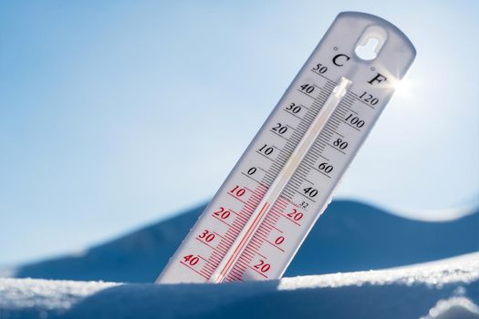 The thermometer lies on the snow in winter showing a negative temperature.Meteorological conditions in a harsh climate in winter with low air and ambient temperatures.Freeze in wintertime.Sunny winter