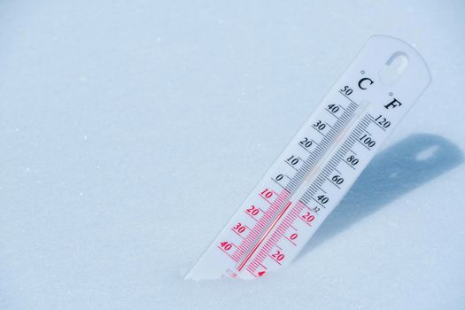 The thermometer lies on the snow in winter showing a negative temperature.Meteorological conditions in a harsh climate in winter with low air and ambient temperatures.Freeze in wintertime.Sunny winter