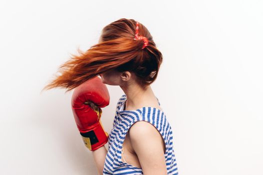 woman practicing a blow in boxing gloves on a light background striped t-shirt model. High quality photo