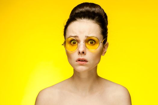 attractive woman with bare shoulders yellow glasses isolated background. High quality photo