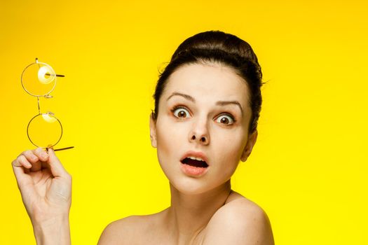 brunette with bare shoulders yellow glasses attractive look. High quality photo